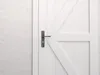 A close-up view of a white door with a metal door handle. Produktbild-Vorschau