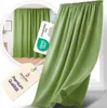 A green curtain is shown hanging in front of a window, with a circular inset showing the same curtain in a room setting. Two tags are also visible, one with a certification logo and the other with brand information. Produktbild-Vorschau