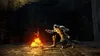 A knight kneels before a bonfire in a dark, stone environment. Podgląd zdjęcia produktu