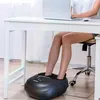 A person is using a foot massager under a desk while working on a laptop. Náhľad obrázku produktu