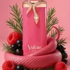 A pink perfume bottle with a gold snake design, surrounded by raspberries, blackcurrants, and rosemary sprigs on a pink background. Voir les images du produit