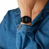 A person wearing a denim jacket and a black digital watch. Anteprima dell’immagine prodotto