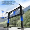 A black adjustable desk frame is shown in an outdoor setting with mountains and a lake in the background. Blue arrows indicate upward movement. Produktbild-Vorschau