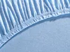 A close-up view of a light blue jersey fitted sheet, showing the elasticized edge and the texture of the fabric. Produktbild-Vorschau