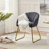 A dark gray accent chair with gold legs is placed on a light rug next to a stack of books and a plant. Podgląd zdjęcia produktu