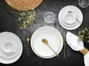 A table setting with white plates, cutlery, and a napkin. Produktbild-Vorschau