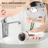 A person is holding an electric callus remover under a running faucet in a sink, demonstrating its waterproof feature. Produktbild-Vorschau