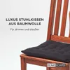 A black seat cushion on a wooden chair, with text overlay. Náhled obrázku produktu