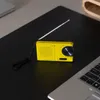 A yellow portable radio with an antenna extended, placed on a black surface next to a laptop. Produktbild-Vorschau