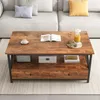 A brown and black coffee table with a shelf and drawers, placed in a living room setting. Náhľad obrázku produktu