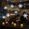 A window display decorated with snowflake lights and LED candles, with people visible inside a cafe. Anteprima dell’immagine prodotto