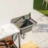 An outdoor sink mounted on a wall next to a marble countertop, with a tiled patio and grass in the background. Anteprima dell’immagine prodotto