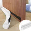 A white door draft stopper is shown attached to the bottom of a wooden door. Náhled obrázku produktu