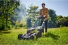 A man is mowing a lawn with a cordless lawnmower. Produktbild-Vorschau