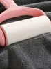 A close-up of a lint roller with a pink handle on a gray textured surface. Produktbild-Vorschau