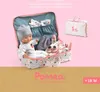 A baby doll and its accessories are displayed inside an open suitcase, with a smaller matching suitcase beside it, against a pink background. Anteprima dell’immagine prodotto