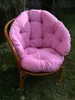 A pink cushion set for a rattan garden chair is placed on the grass. Produktbild-Vorschau