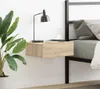 A floating nightstand next to a bed with a lamp and a cup on it. Produktbild-Vorschau