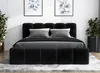 A black upholstered bed with a headboard and a bench at the foot of the bed, set in a bedroom with artwork on the wall and plants. Produktbild-Vorschau