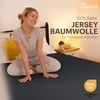 A woman sitting on a bed with a fitted sheet. Produktbild-Vorschau