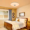 A bedroom with a bed, window, and a ceiling light. Voir les images du produit