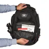A person is placing items into an open backpack. Produktbild-Vorschau