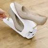 A hand is holding a white shoe organizer with two pairs of glittery gold high heels. Produktbild-Vorschau