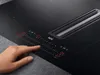 A person's hand is touching the control panel of a modern black induction hob with an integrated extractor fan. Anteprima dell’immagine prodotto