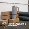 A grey Stanley tumbler with a straw sits on yoga blocks, with yoga mats in the background. Produktbild-Vorschau