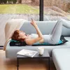 A woman is lying on an acupressure mat and pillow on a sofa, using her phone. Náhľad obrázku produktu