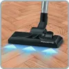 A vacuum cleaner head on a wooden floor with blue arrows indicating airflow. Produktbild-Vorschau