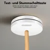 A smoke detector is shown mounted on a ceiling, with a wooden pole extending from its center, suggesting it can be tested or silenced from the floor. Produktbild-Vorschau
