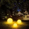 Three illuminated spherical garden lights are placed on a grassy lawn at night, with trees and a building in the background. Anteprima dell’immagine prodotto