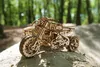 A wooden model motorcycle with a sidecar is placed on a dirt path in a forest. Anteprima dell’immagine prodotto