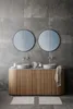 A modern bathroom vanity with two sinks, two round mirrors, and wooden cabinetry. Produktbild-Vorschau