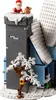A close-up view of a LEGO Christmas-themed building set, featuring Santa Claus on top of a tower, a snowy tree, and parts of a building. Podgląd zdjęcia produktu