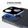 A close-up, angled view of a black camera lens protector being placed onto the camera module of a dark-colored smartphone. Blue light rays emanate from the phone's camera lenses towards the protector, illustrating the fit and adhesion. Produktbild-Vorschau