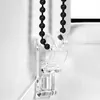 Close-up of a black beaded chain and a clear plastic bracket for a roller blind. Náhled obrázku produktu