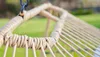 Close-up of a hammock chair's woven edge and ropes, with a blurred green background. Podgląd zdjęcia produktu