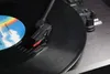 A close-up shot of a record player's tonearm and needle on a spinning vinyl record. Produktbild-Vorschau