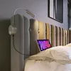 A close-up view of a bed with a tufted headboard, featuring a bedside lamp and a tablet. Produktbild-Vorschau