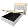 A bed frame with its mattress support lifted to reveal storage space underneath. The headboard has integrated shelving and LED lighting. Produktbild-Vorschau