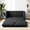 A dark gray sofa bed is unfolded and laid out on a light-colored rug in a room with a plant and a bookshelf. Produktbild-Vorschau