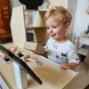 A young child playing with a wooden toy cash register. Produktbild-Vorschau