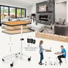 A living room scene with a modern fireplace and furniture, featuring a height-adjustable table. Produktbild-Vorschau
