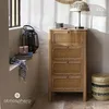 A wooden cabinet with rattan drawers is placed in a room with natural light, next to a window with blinds. Decorative items like a lantern, a candle, and a basket are also present. Podgląd zdjęcia produktu