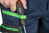 A person's hand holds a screwdriver with a NEO TOOLS logo, attached to a green loop on dark blue work pants. Produktbild-Vorschau