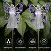 Two solar-powered garden lights shaped like fairies with purple flowers on their wings, set against a backdrop of green leaves. Náhľad obrázku produktu