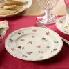 A table setting with a floral patterned plate, bread, and a glass. Podgląd zdjęcia produktu