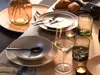 A table setting with plates, bowls, cutlery, glasses, and candles, suggesting a meal or event. Produktbild-Vorschau